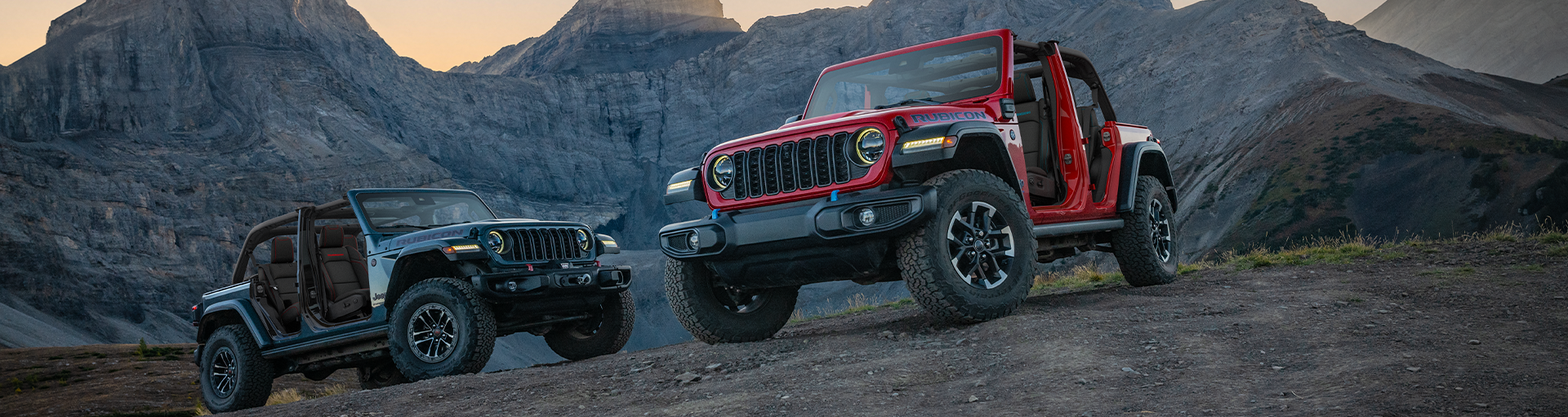 Two Jeep Wranglers parked off-road at an angle near each other by mountains