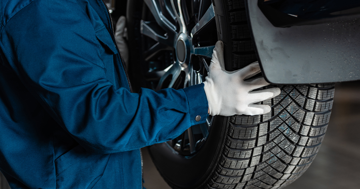 A service technician holding the tires of a vehicle lifted in the service center