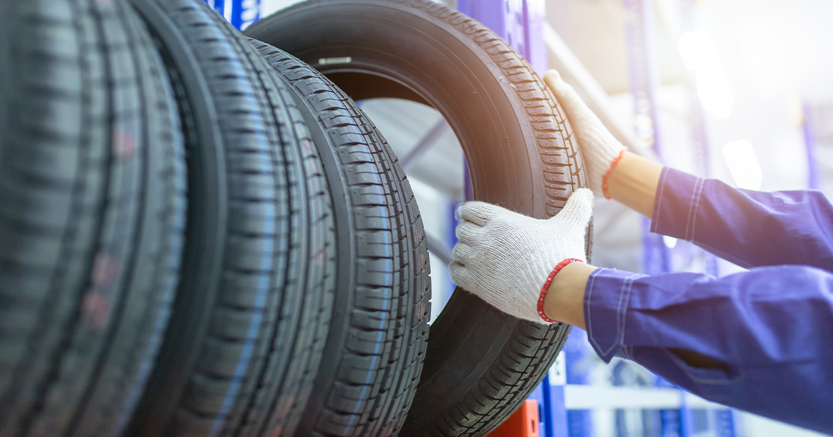 A close-up of a service technician pulling a tire from a row of tires on a rack